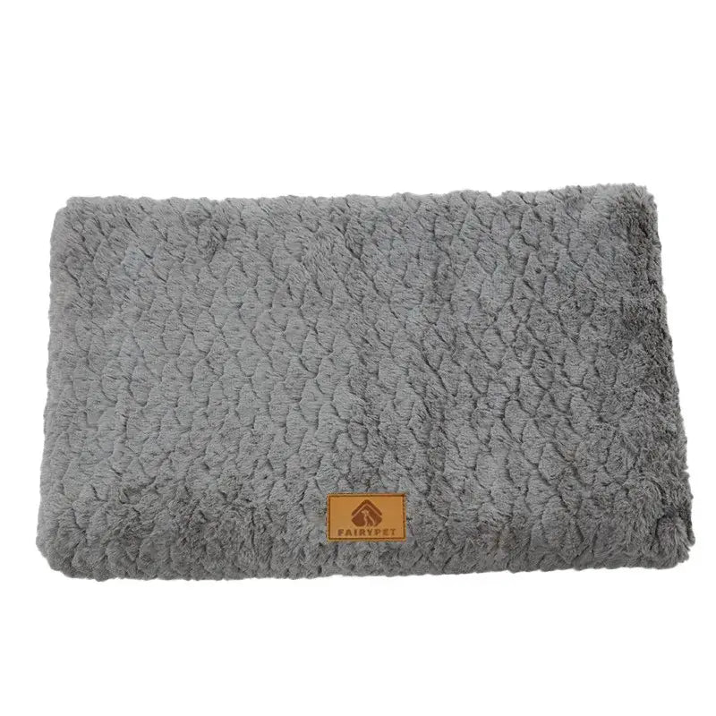 Plush gray pet bed or mat with a textured surface and a small leather tag.