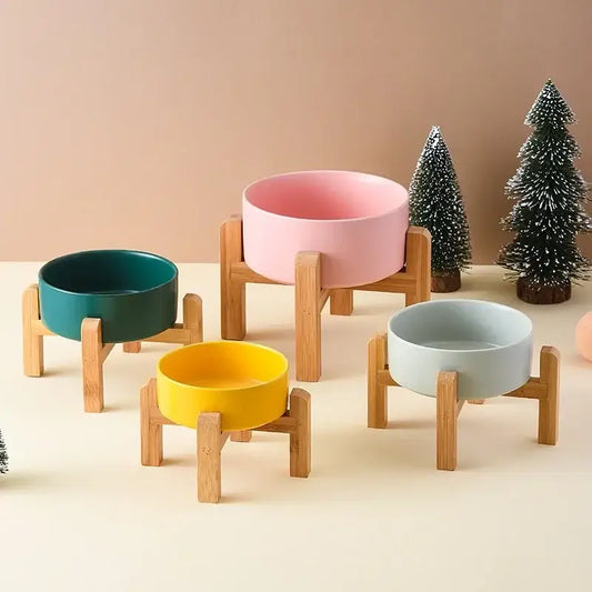 Colorful ceramic bowls on wooden stands with miniature Christmas trees in the background.