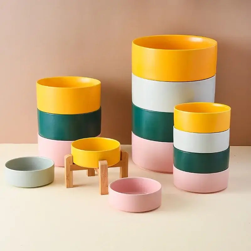 Colorful stackable ceramic planters or containers in yellow, green, white, and pink.