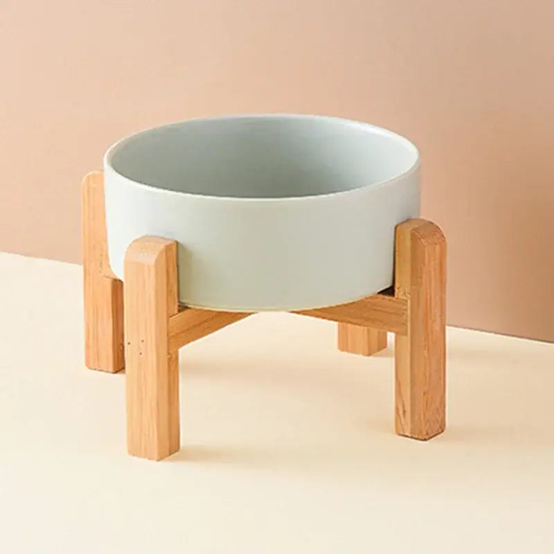 White ceramic bowl resting on a wooden stand with four legs.