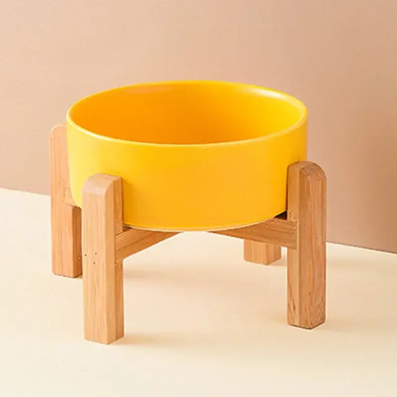 Yellow ceramic bowl on a wooden stand with four legs.