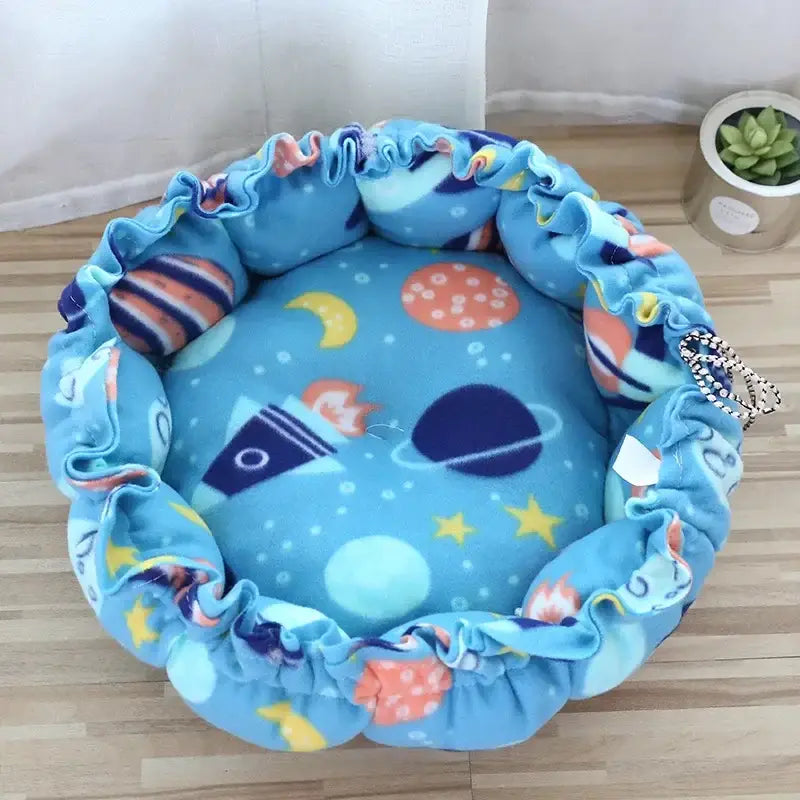 Circular blue pet bed with a space-themed pattern and ruffled edges.