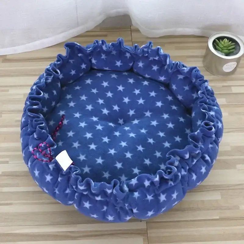 Circular blue pet bed with white star pattern and ruffled edges.