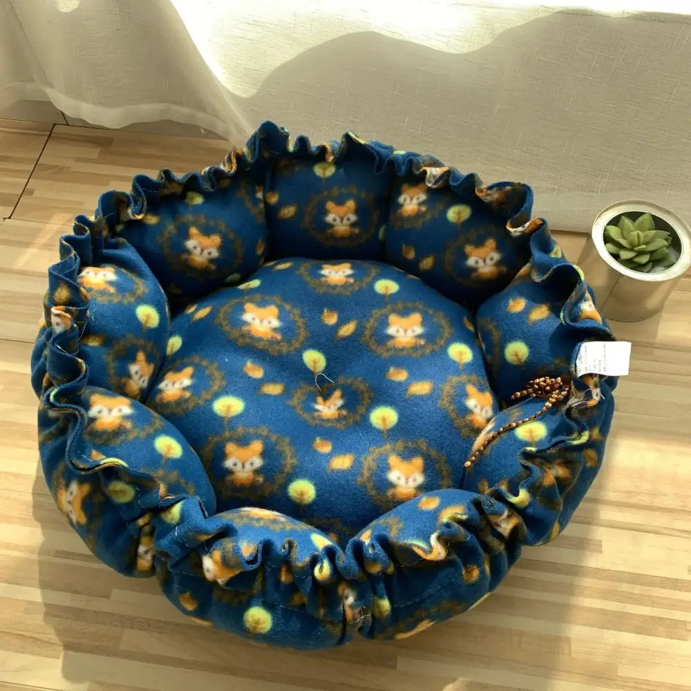 Circular pet bed with a blue floral pattern and ruffled edges.