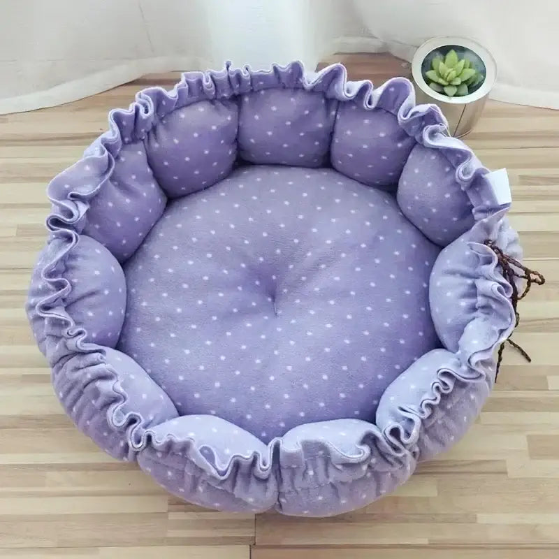 Circular purple pet bed with white polka dots and ruffled edges.