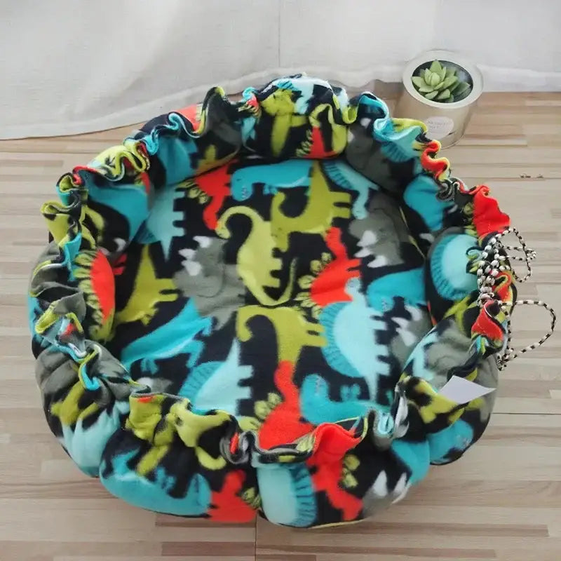 Colorful round pet bed with a dinosaur print pattern.