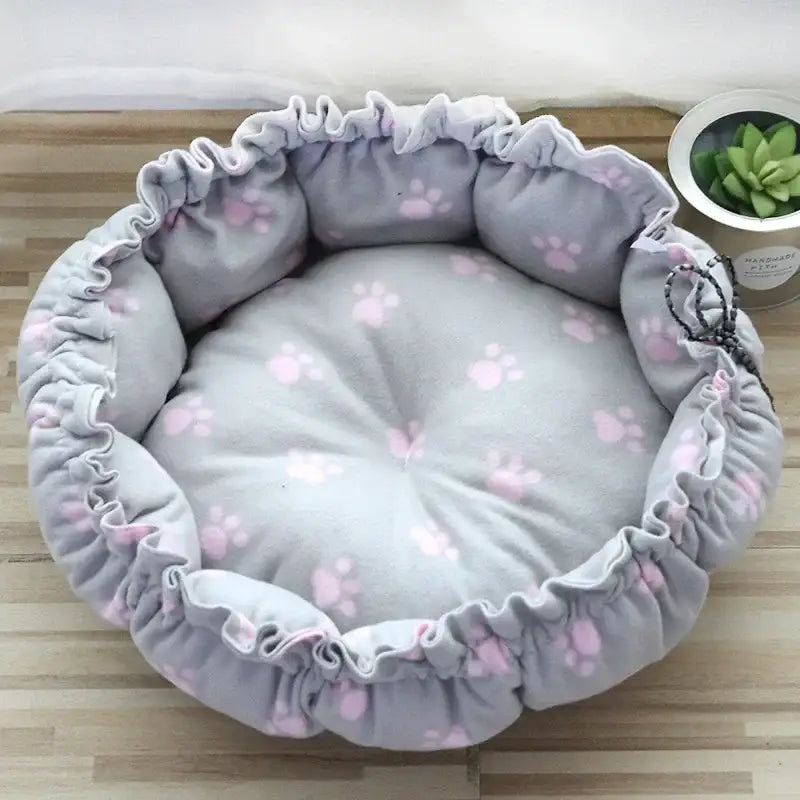 Soft, round pet bed with gray fabric and pink paw print pattern.