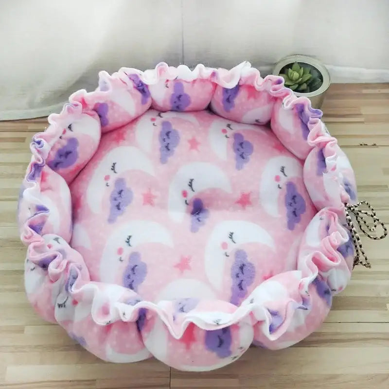 Soft, round pet bed with pink and purple watercolor-like patterns and ruffled edges.