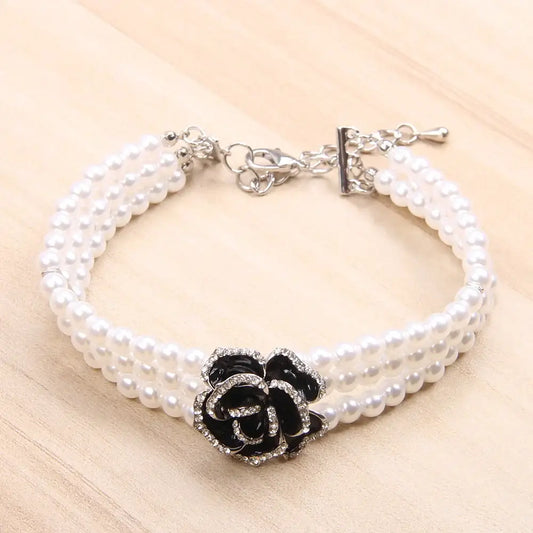 Pearl bracelet with a black and silver rose-shaped centerpiece.