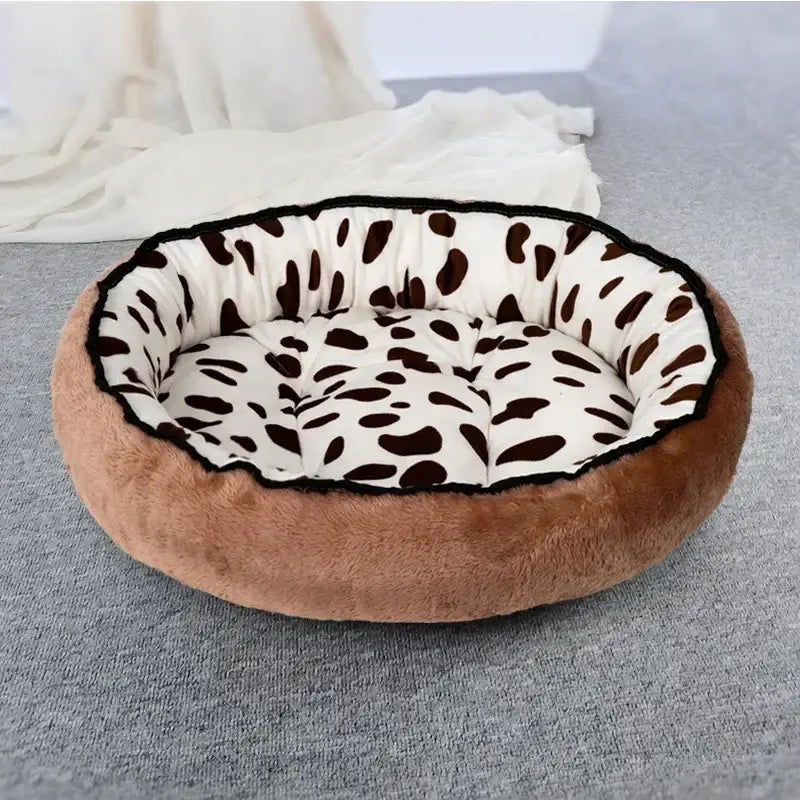 Circular pet bed with a brown exterior and a white interior featuring black spots.