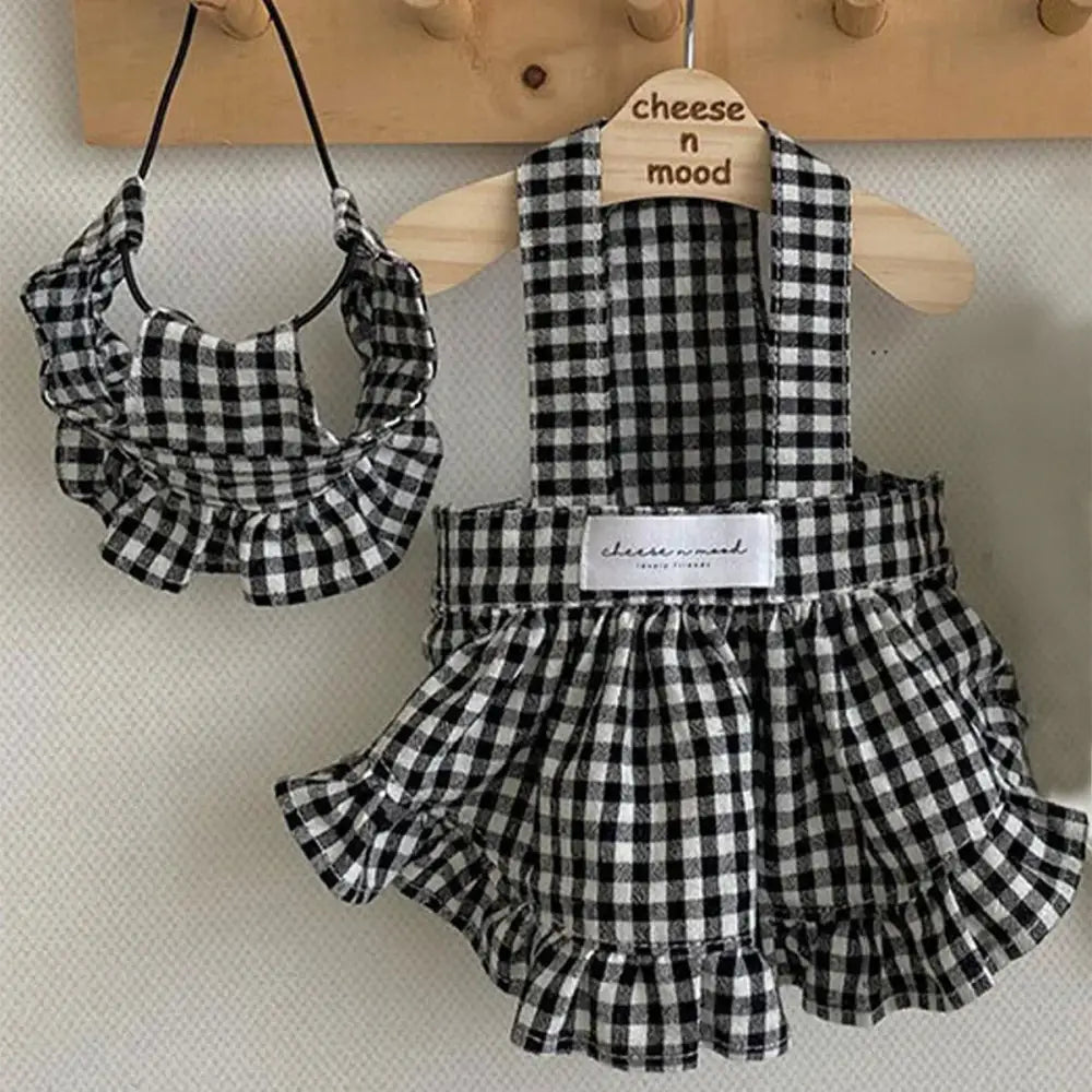 Black and white gingham patterned baby outfit consisting of a ruffled skirt, vest top, and matching bib.