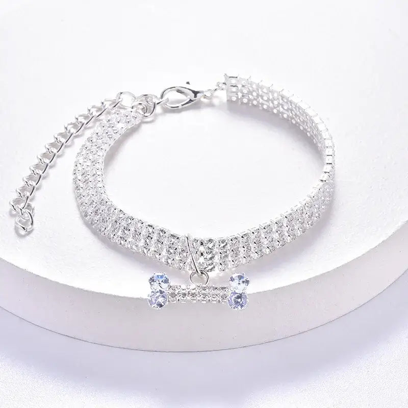 Sparkling silver bracelet with a dangling bone-shaped charm adorned with crystals.