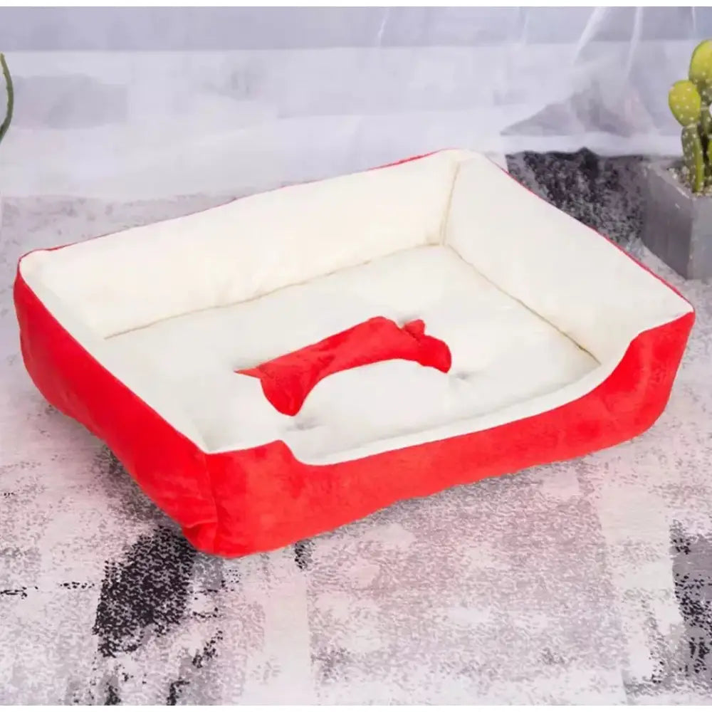 Red and white rectangular pet bed with a bone-shaped toy inside.