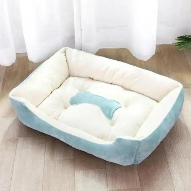 Soft, rectangular pet bed with light blue trim and a bone-shaped cushion.