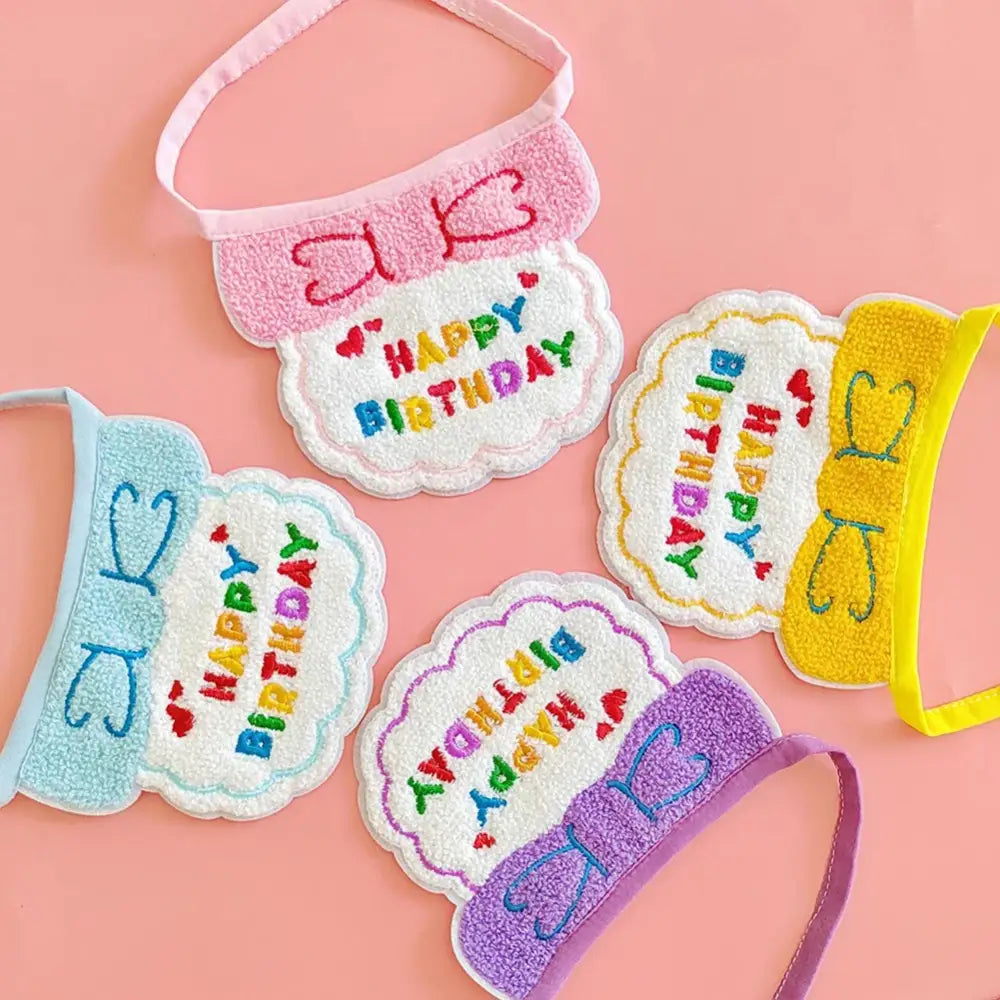 Colorful ’Happy Birthday’ bibs or drool catchers with bow designs.