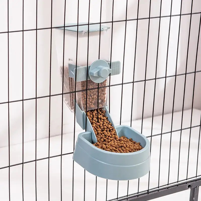 Automatic pet feeder attached to a wire cage, dispensing dry food into a blue bowl.