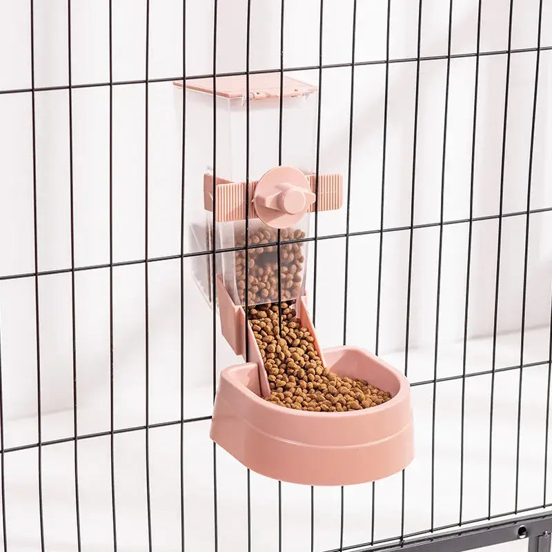 Pink plastic pet feeder attached to a wire cage, filled with dry food pellets.