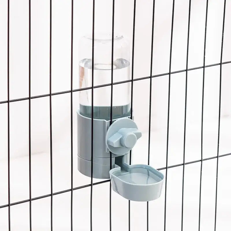 Water bottle with an attached pet drinking bowl mounted on a wire cage.