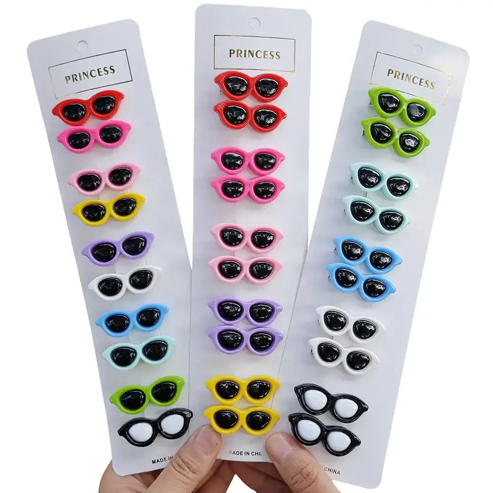 Sets of colorful miniature sunglasses displayed on white cardboard strips labeled ’Princess’.