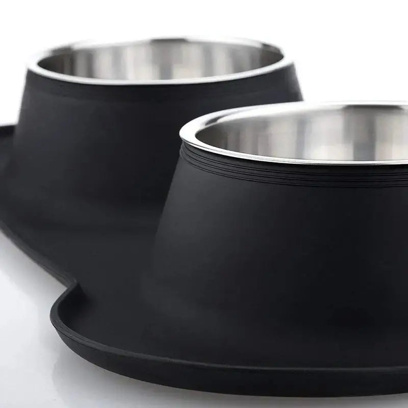 Matte black pet food bowls with shiny metal interiors on a raised base.