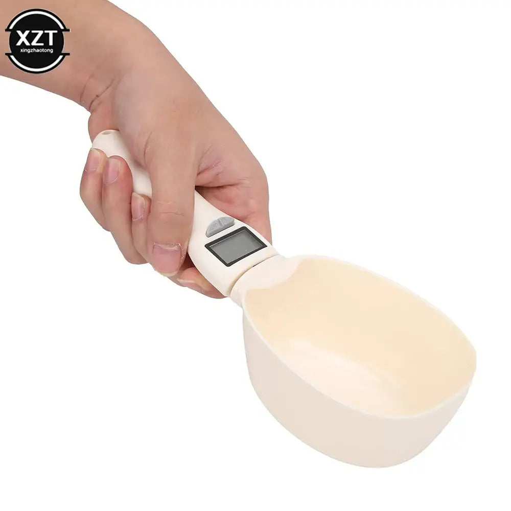 Digital kitchen scale in the shape of a spoon with a round weighing bowl.