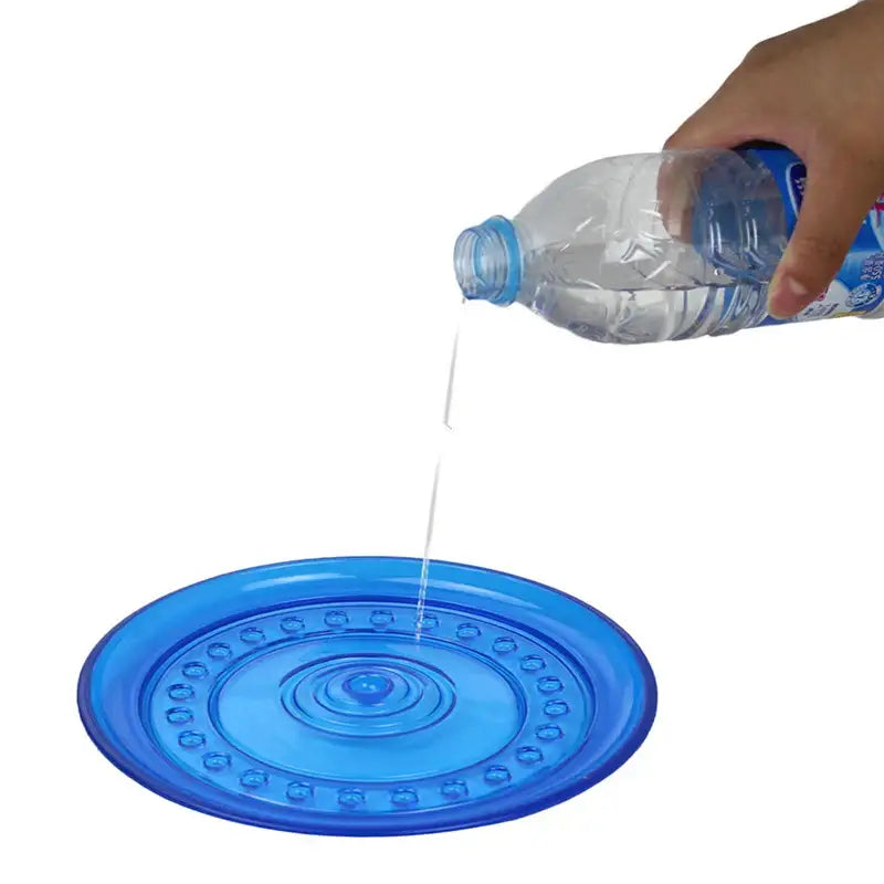 Blue plastic plate with concentric circular patterns catching water being poured from a bottle.