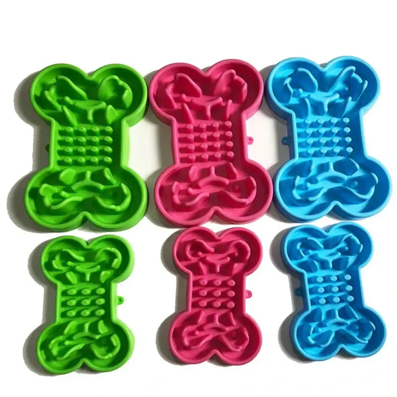 Colorful bone-shaped silicone dog food bowls or slow feeder mats in green, pink, and blue.