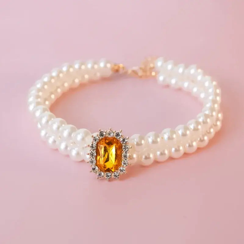 Pearl bracelet with a central amber gemstone surrounded by small diamonds.