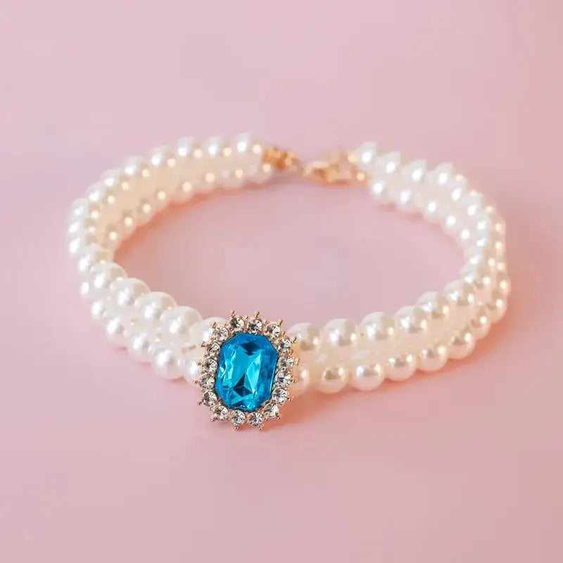 Pearl bracelet with a central blue gemstone surrounded by smaller diamonds.