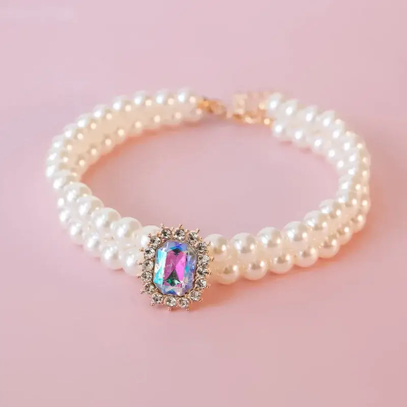 Pearl bracelet with a colorful gemstone centerpiece surrounded by small diamonds.