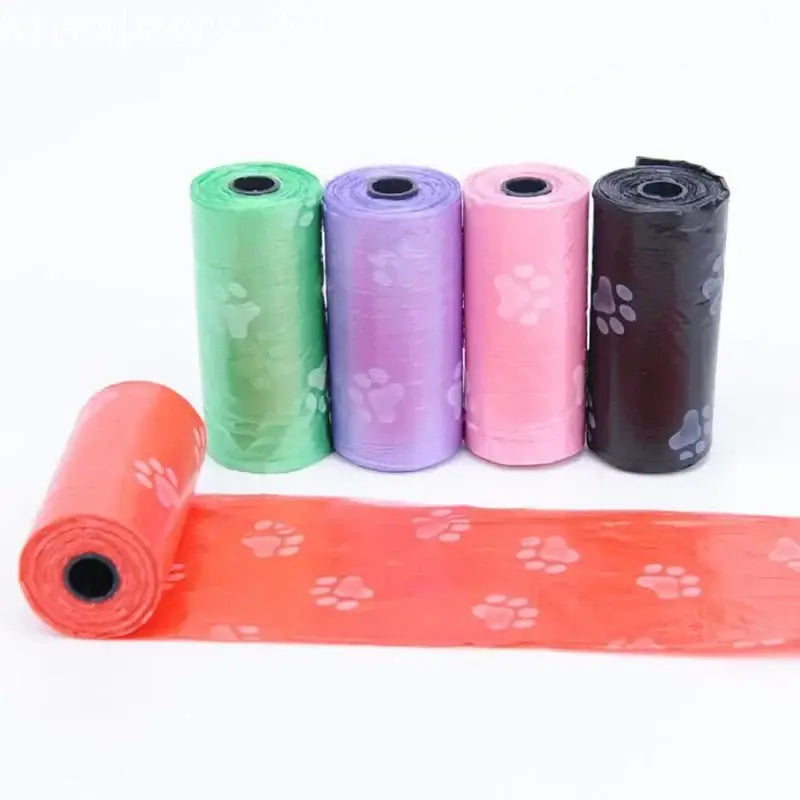 Colorful rolls of plastic dog waste bags with paw print designs.