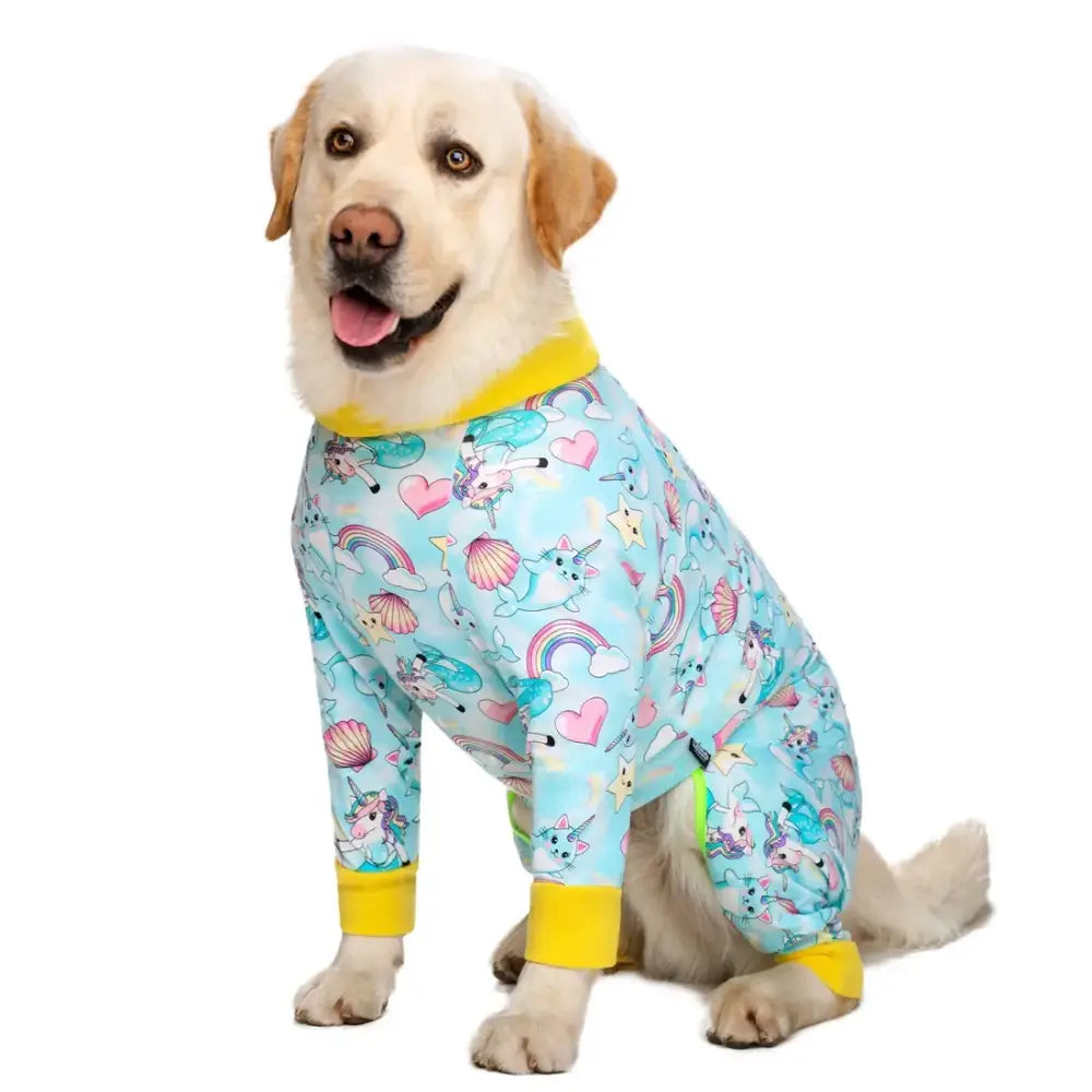 Yellow Labrador wearing colorful pajamas with unicorn and rainbow patterns.