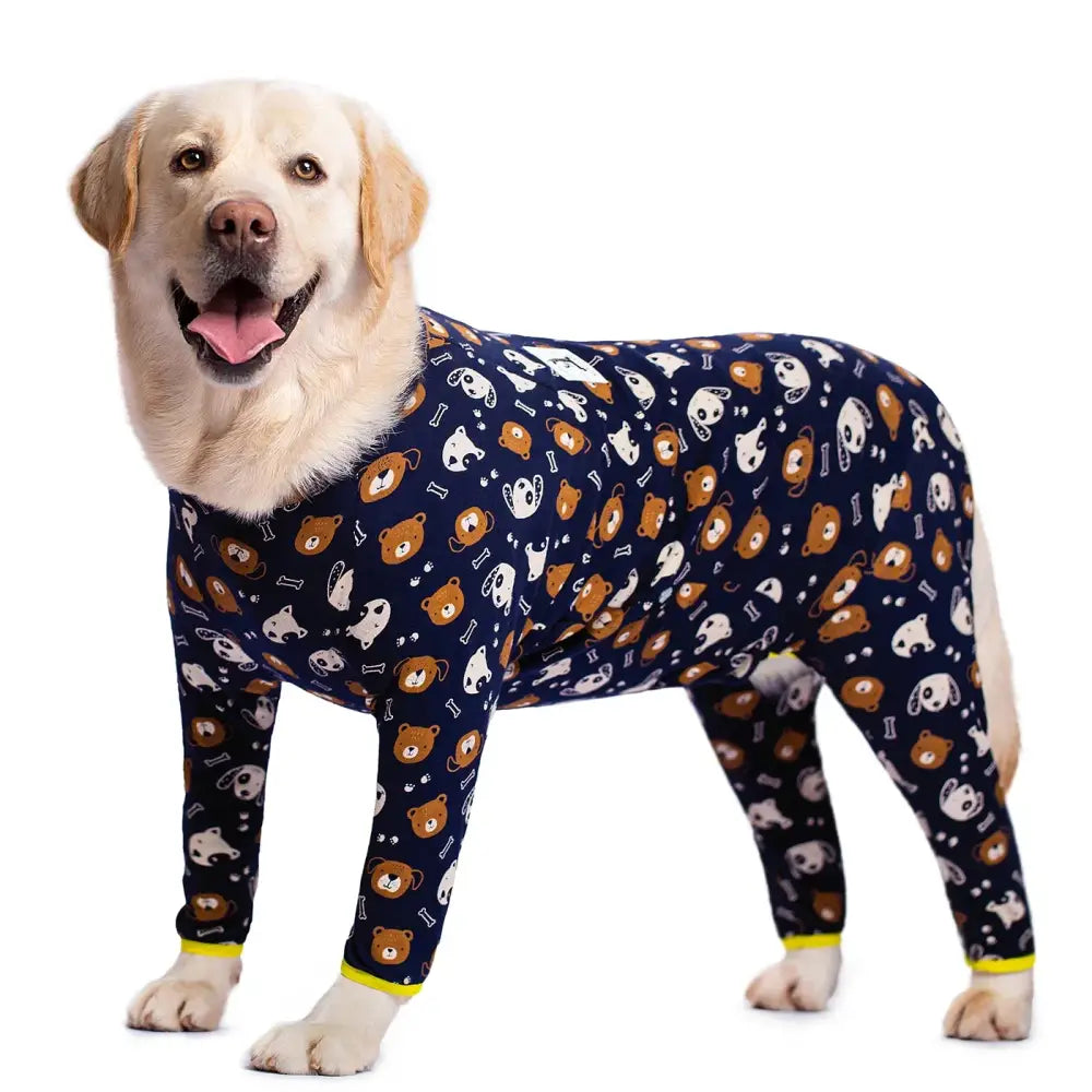 Yellow Labrador retriever wearing a navy blue pajama outfit covered in cartoon animal face prints.