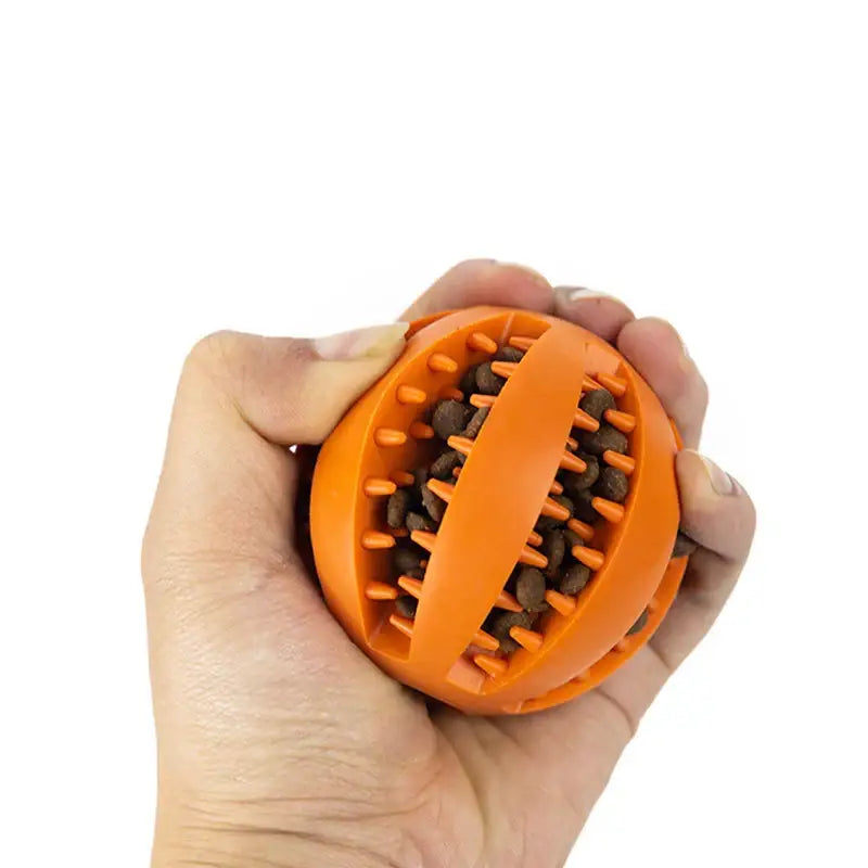 Orange rubber ball with textured grooves held in a hand.