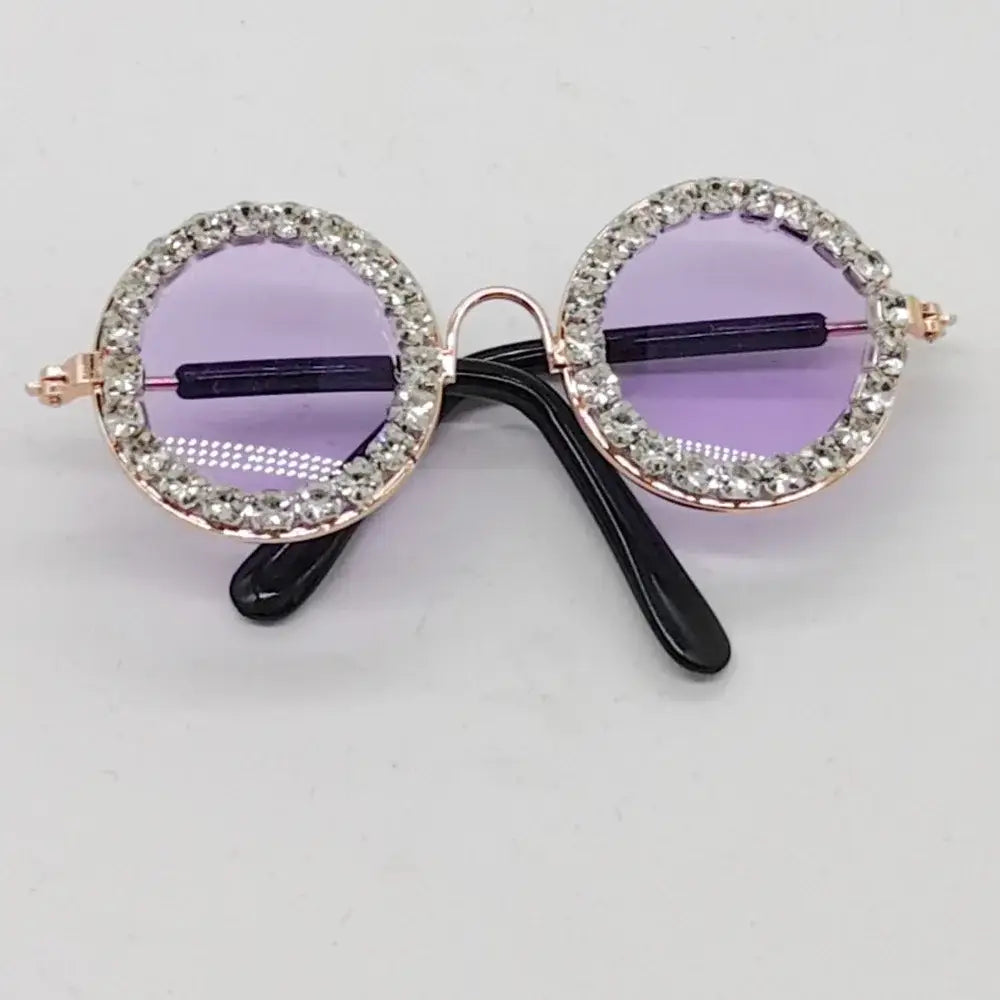 Pair of round sunglasses with rhinestone-encrusted frames and purple lenses.