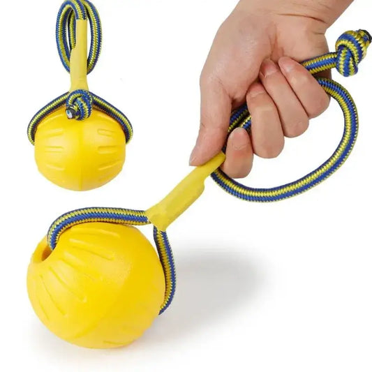 Yellow ball toy with attached rope handle for throwing or swinging.