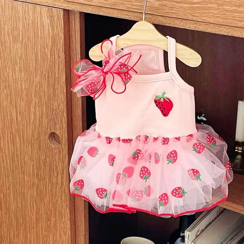 Pink strawberry-themed tutu dress for a young child hanging on a hanger.