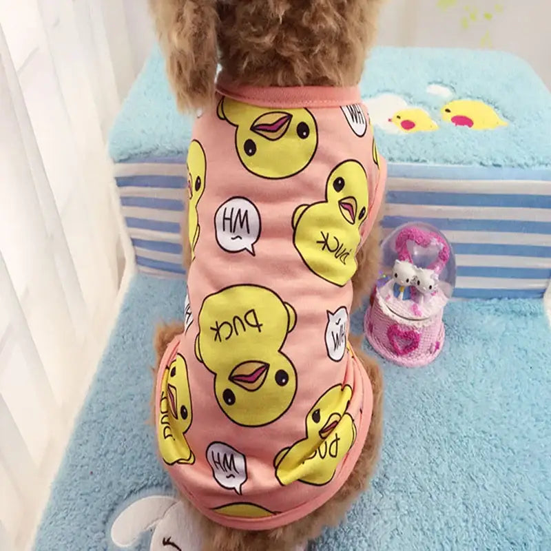 Dog wearing a pink pajama outfit with yellow smiley face emojis printed on it.