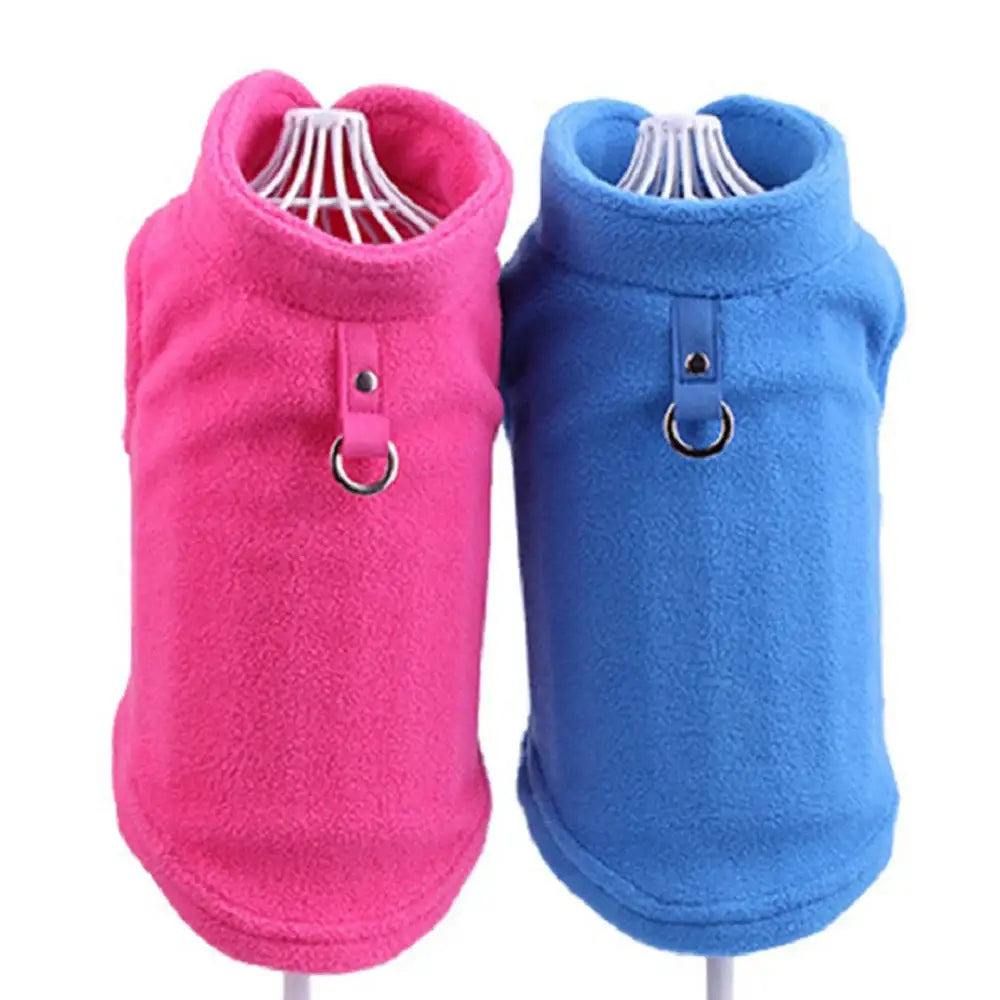 Two fleece dog vests, one pink and one blue, with high collars and metal rings attached.