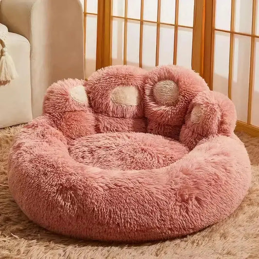 Fluffy pink round pet bed with a raised, paw-shaped backrest.