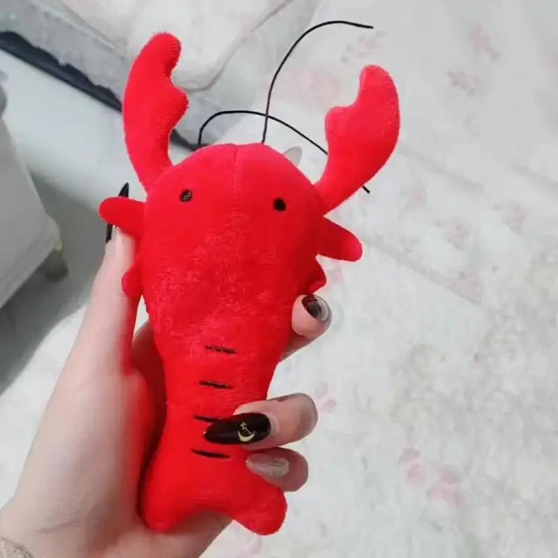 Bright red plush toy lobster with simple facial features and antennae.