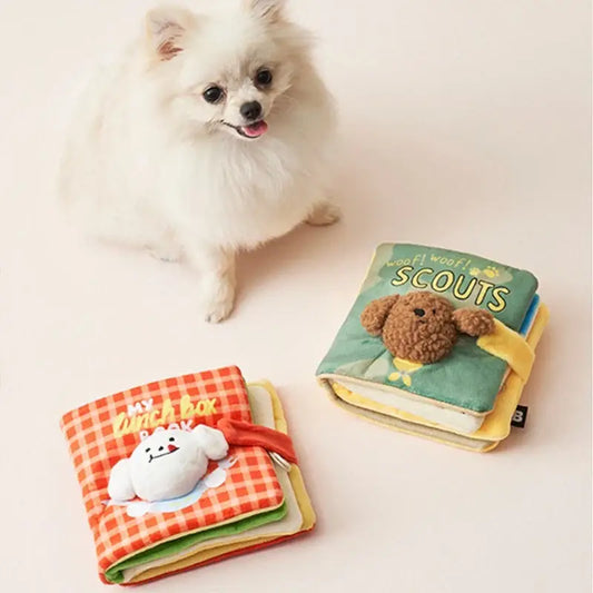 Fluffy white Pomeranian dog sitting next to two soft children’s books.