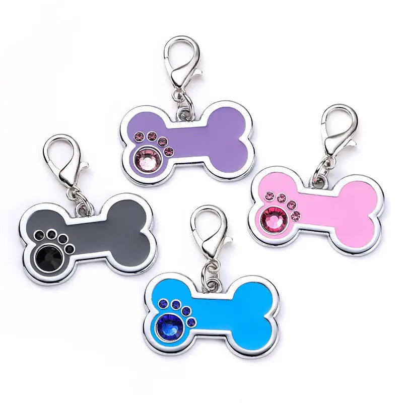 Colorful bone-shaped pet ID tags with paw print designs and metal clasps.