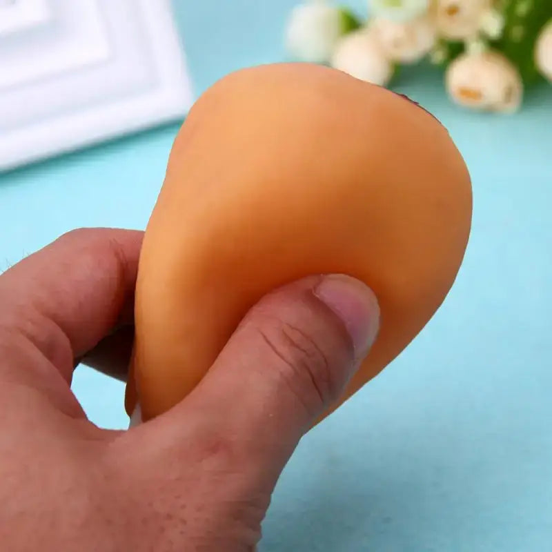 Peach-colored silicone or rubber stress ball being squeezed by a hand.