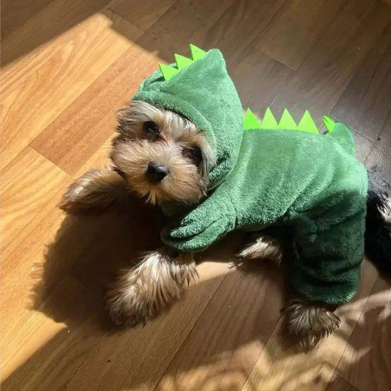 Dog wearing a green dinosaur costume.