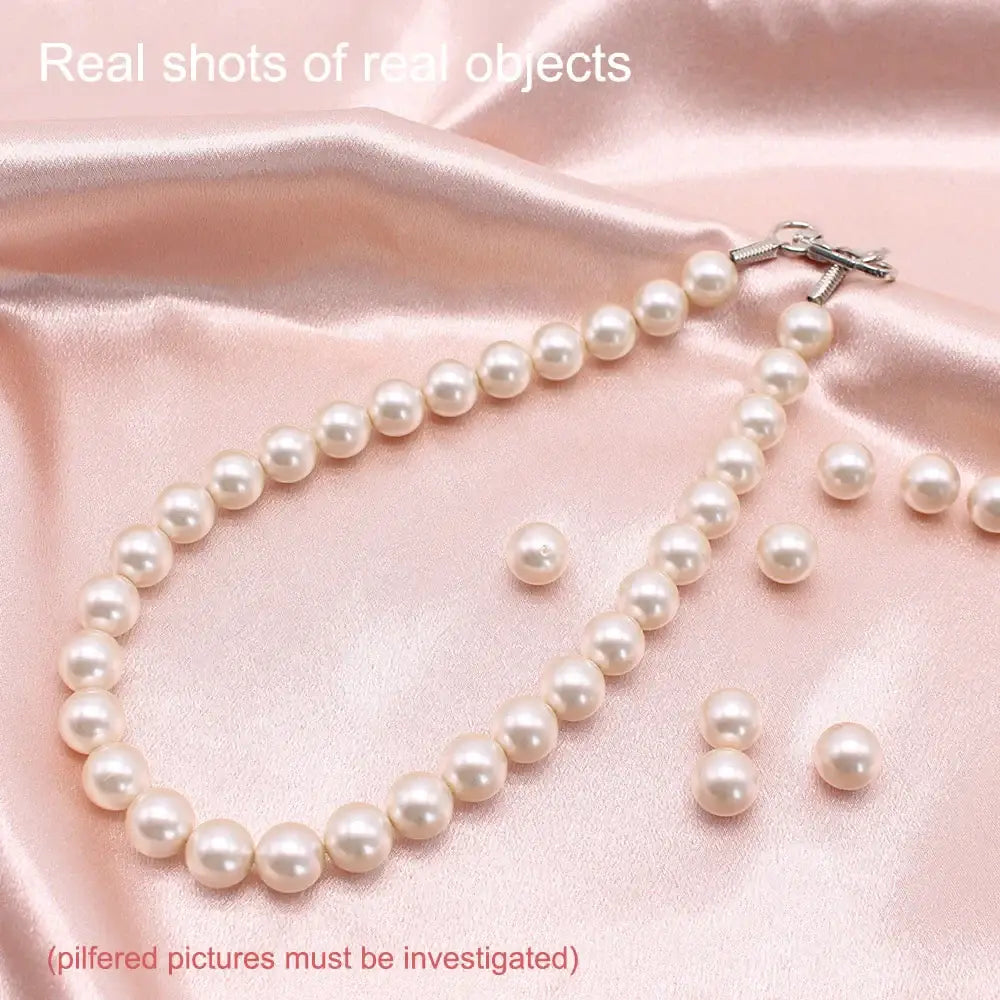 Pearl necklace with matching loose pearls on pink fabric.