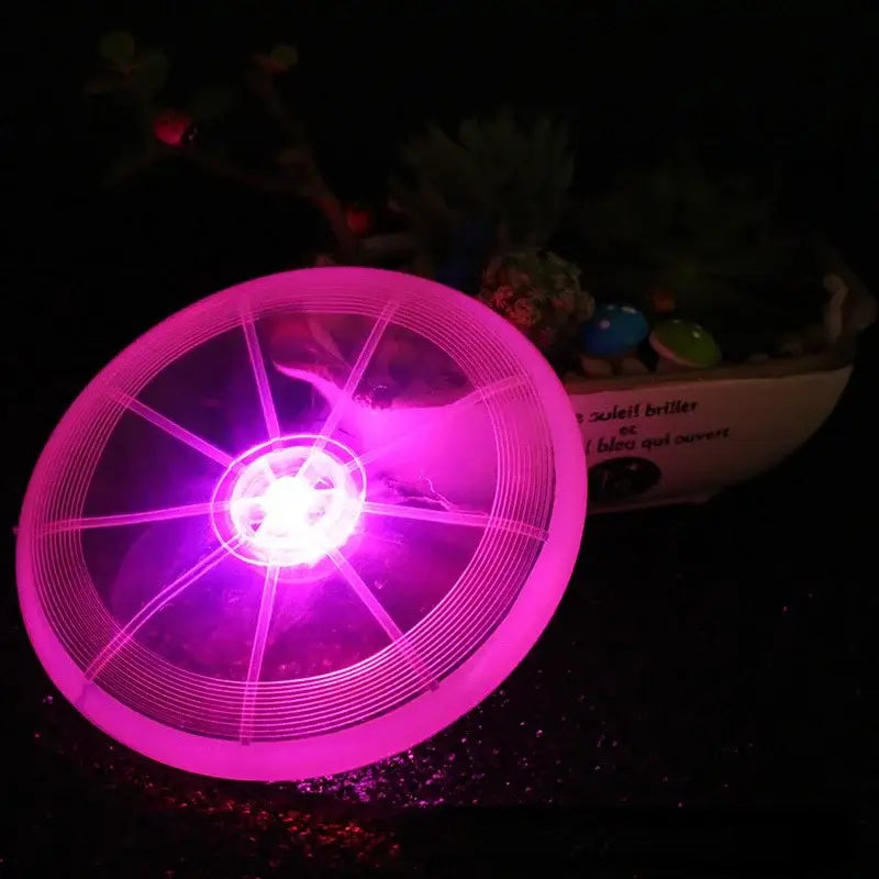 Glowing pink frisbee or flying disc with illuminated spokes and center.