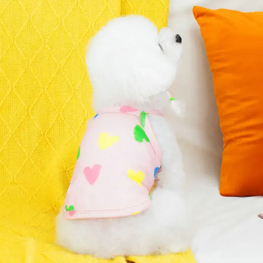 White plush toy dog wearing a pink heart-patterned shirt.