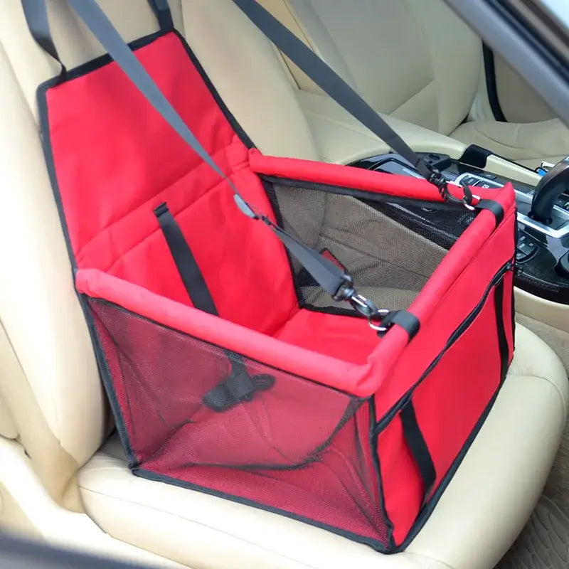 Red pet carrier seat for cars with mesh sides and safety straps.