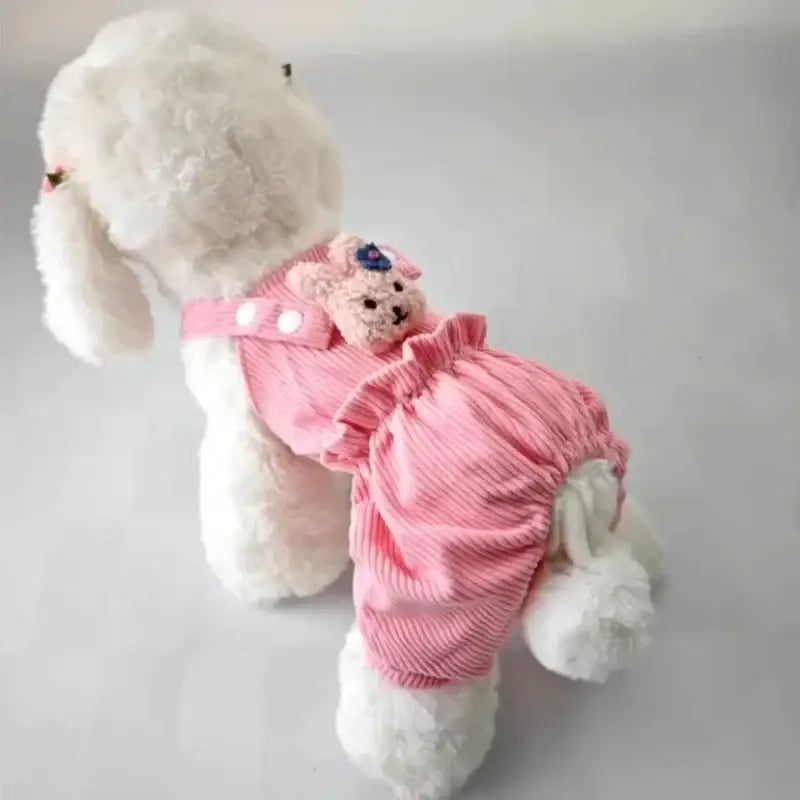 White stuffed dog wearing a pink outfit with a small plush bear attached.